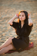 Young pretty hispanic gir in black sit on sand