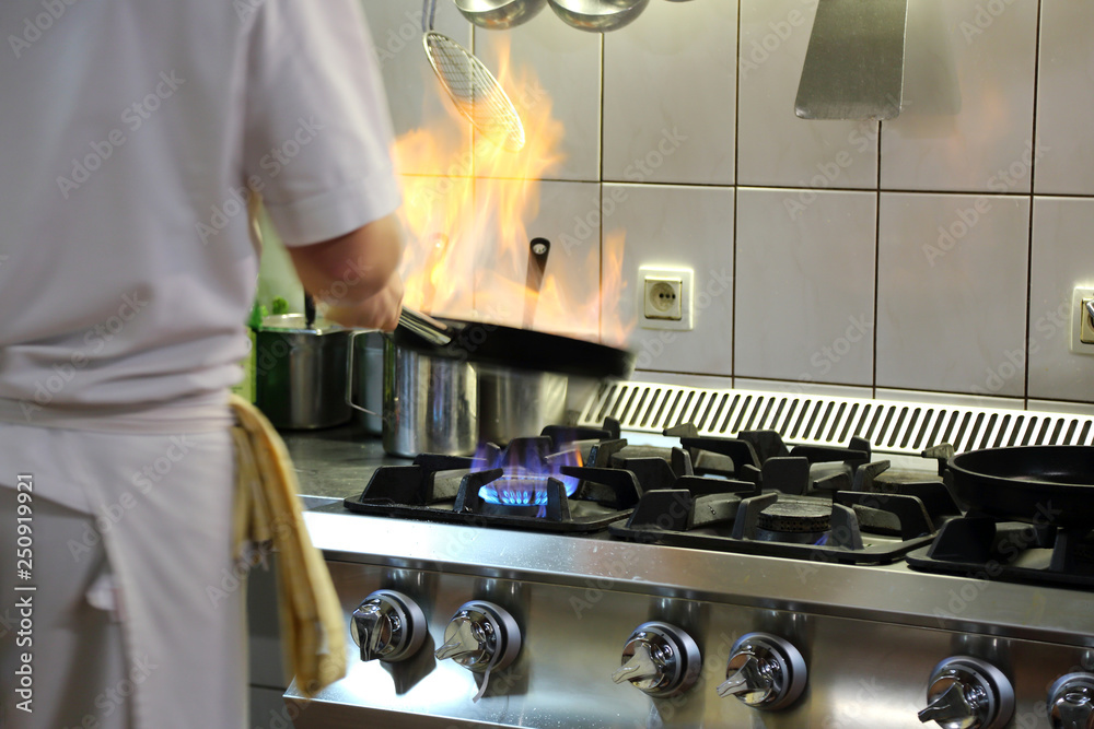 Obraz na płótnie Ogień na patelni w czasie pieczenia, kucharz w kuchni. w salonie