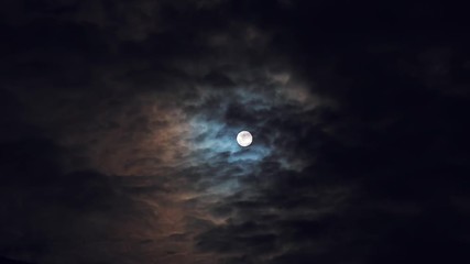 Wall Mural - Full moon or supermoon in night blue sky with fast moving clouds, dramatic mysterious atmosphere, toned