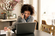 © Cavan Images - Woman at home using phone and laptop