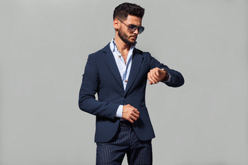 Wall Mural - Elegant young handsome man in suite wearing glasses. Studio fashion portrait.