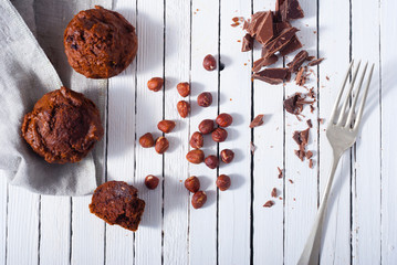 Wall Mural - broken chocolate muffin and hazelnuts, fork on white wood table