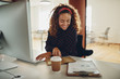 © Flamingo Images - Smiling young businesswoman working at her desk in an office