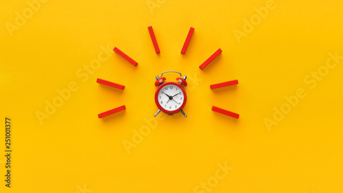 Fotografía Alarm clock with red dominoes on yellow background