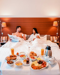 youngcouple men and woman having breakfast in bed