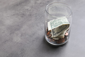 Donation jar with money on grey background. Space for text