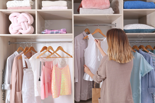 Cuadros en Lienzo Woman choosing outfit from large wardrobe closet with stylish clothes and home s