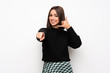 © luismolinero - Young woman over white wall making phone gesture and pointing front