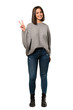 © luismolinero - A full-length shot of a Young woman smiling and showing victory sign over isolated white background