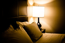 Illuminated Lamp And Bed In Dimly Lit Bedroom At Night