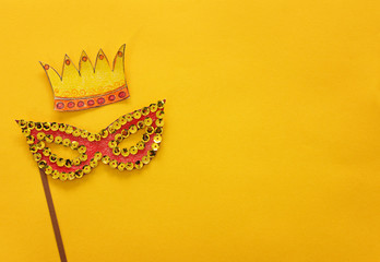 Wall Mural - carnival party celebration concept with paper mask and crown over yellow background. Top view. Flat lay