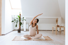 Meditating and yoga on maternity. Pregnant woman meditating while sitting in yoga position at home. Healthy pregnancy, lifestyle