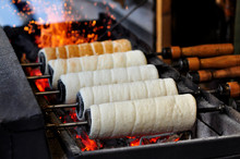 Traditional Hungarian pastry chimney cake or kurtos kalacs is baking over the open charcoal grill on the annual traditional Christmas market