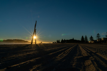 Canvas Print - Tracks from beach grooming leading away towards sunrise