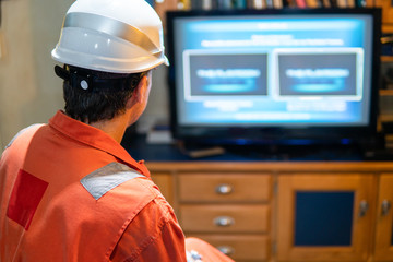 Marine chief officer wearing coverall and helmet on a ship or vessel having fun watching TV. Recreation during at sea