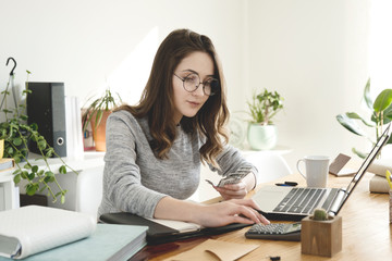 Young business woman counting money at office.