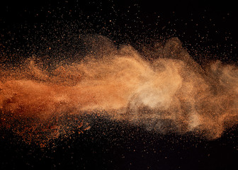 Cocoa powder explosion on black background.