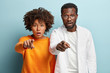 © wayhome.studio  - Ethnic young woman and man groupmates stand closely, point direclty at camera, have surprised expressions, notice astonishing thing in front, isolated over blue background. Omg, its unbelievable
