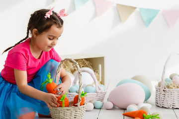 Wall Mural - Cute little child girl wearing bunny ears on Easter day. Girl holding basket with painted eggs.