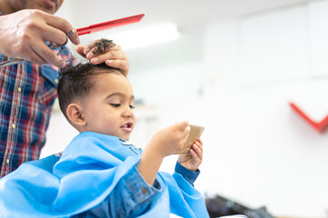 Wall Mural - Cute Boy Getting a Hair Cut in a Barber Shop. Beauty Concept.