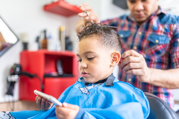 Wall Mural - Cute Boy Getting a Hair Cut in a Barber Shop. Beauty Concept.