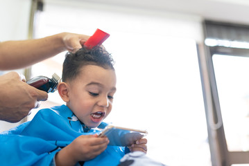 Wall Mural - Cute Boy Getting a Hair Cut in a Barber Shop. Beauty Concept.