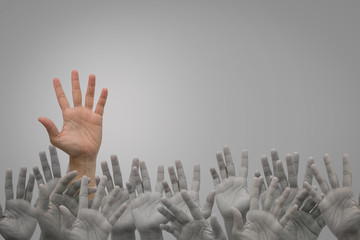 Group of human hands raised high up on grey