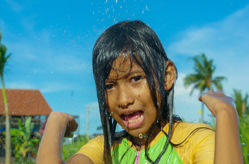 young happy and carefree beautiful child 7 or 8 years old outdoors having shower at a beautiful rice terrace playful under the water wearing cute girl swimsuit