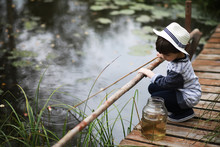A Child In A Campaign Catches Fish In Pond.