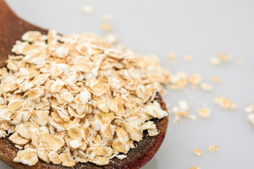 Oats flakes on wooden spoon isolated on white