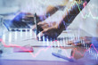 © peshkova - Close up of hands writing with double exposure of business charts. Financial concept.