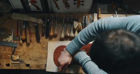 Wall Mural - Slow motion close up of master artisan luthier working on creation of handmade violin  in a workshop. Shot in 8K. Concept of spiritual instrument, handmade, art, orchestra, artisan, passion for music