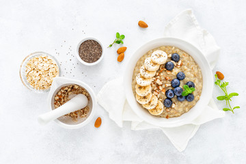 Healthy vegetarian food, oatmeal with fresh blueberry, banana, almond nuts and chia seeds for breakfast, view from above