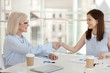© fizkes - Happy businesswomen different ages shaking hands in office