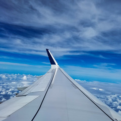 Airplane flying high above the beautiful blue sky with white fluffy clouds