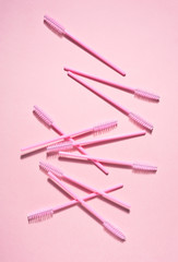 Creative concept beauty photo of lashes extensions brush on pink background.