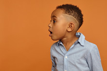 Wow. Amazed Astonished Handsome Afro American Child With Stylish Hairdo Posing Isolated At Blank Copyspace Studio Wall, Opening Mouth Widely, Expressing Great Surprise And Fascination, Jaw Dropped