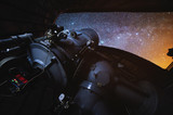 Fototapeta Londyn - Close-up of an astronomical telescope in an observatory. Open telescope dome with stars and the milky way. Night photo on a long exposure