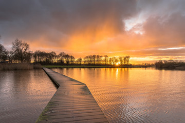 Poster - Wooden walkway in lake under orange sunset