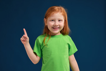 close up photo of little redhead emotional girl posing before camera on blue background