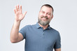 © RealPeopleStudio - Polite ymature man with beard dressed in denim shirt saying hi, waving with hand