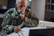 © Drazen - Mature sergeant in military uniform doing paperwork at office desk.