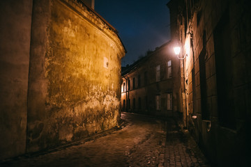 Ancient narrow night Vilnius street with old architecture and winter background