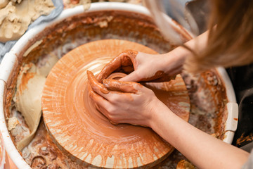 Craftsman hands making pottery bowl. Woman working on potter wheel . Family business shop sculpts pot from clay view top.