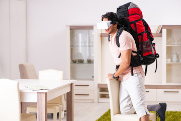 Young male tourist with virtual glasses preparing for trip 