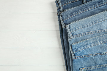 Wall Mural - Different jeans folded on a white wooden background, space for text