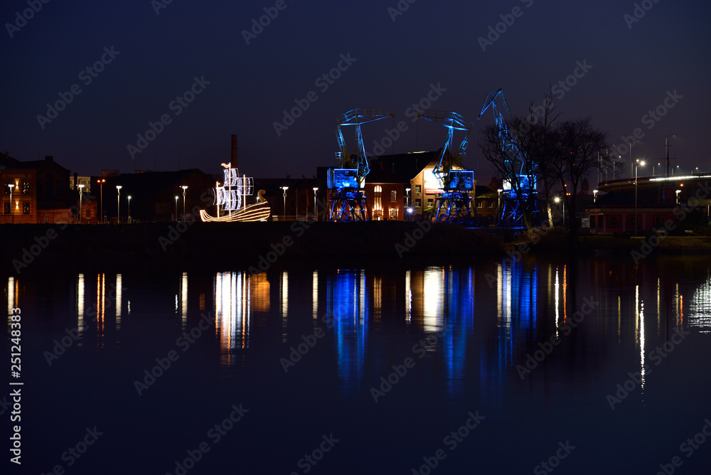 Colorfully illuminated antique cranes on the quay of Szczecin Łasztownia.  - obrazy, fototapety, plakaty 