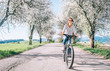 © Soloviova Liudmyla - Happy smiling woman rides a bicycle on the country road under blossom trees. Spring is comming concept image.