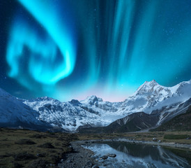 Wall Mural - aurora borealis over the snowy mountains, coast of the lake and reflection in water. northern lights