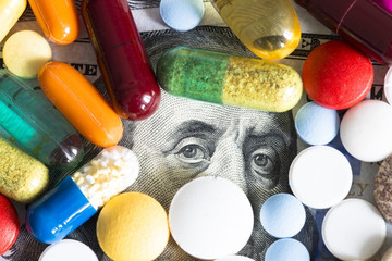 Health care or medical cost concept with many colourful pills on US dollar cash banknote